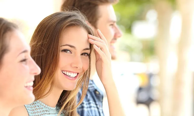 A young woman smiling confidently after a dental bonding replacement procedure, showing bright, natural-looking teeth.