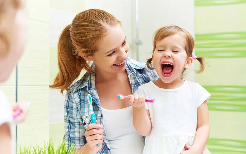 Mother and daughter brushing teeth