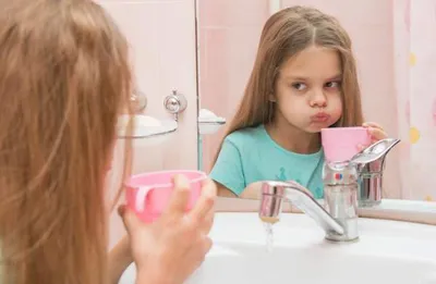 Girl in bathroom rinsing her teeth after brushing