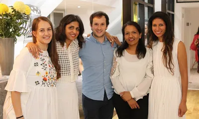 The West House Dental team standing together smiling at their first birthday celebration in Pinner, featuring yellow flowers and festive decorations in the background.